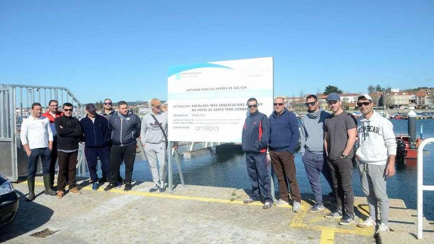 Los pescadores junto al cartel de obra del pantalán, en el que se indica que costó 200.000 euros. // Noé Parga