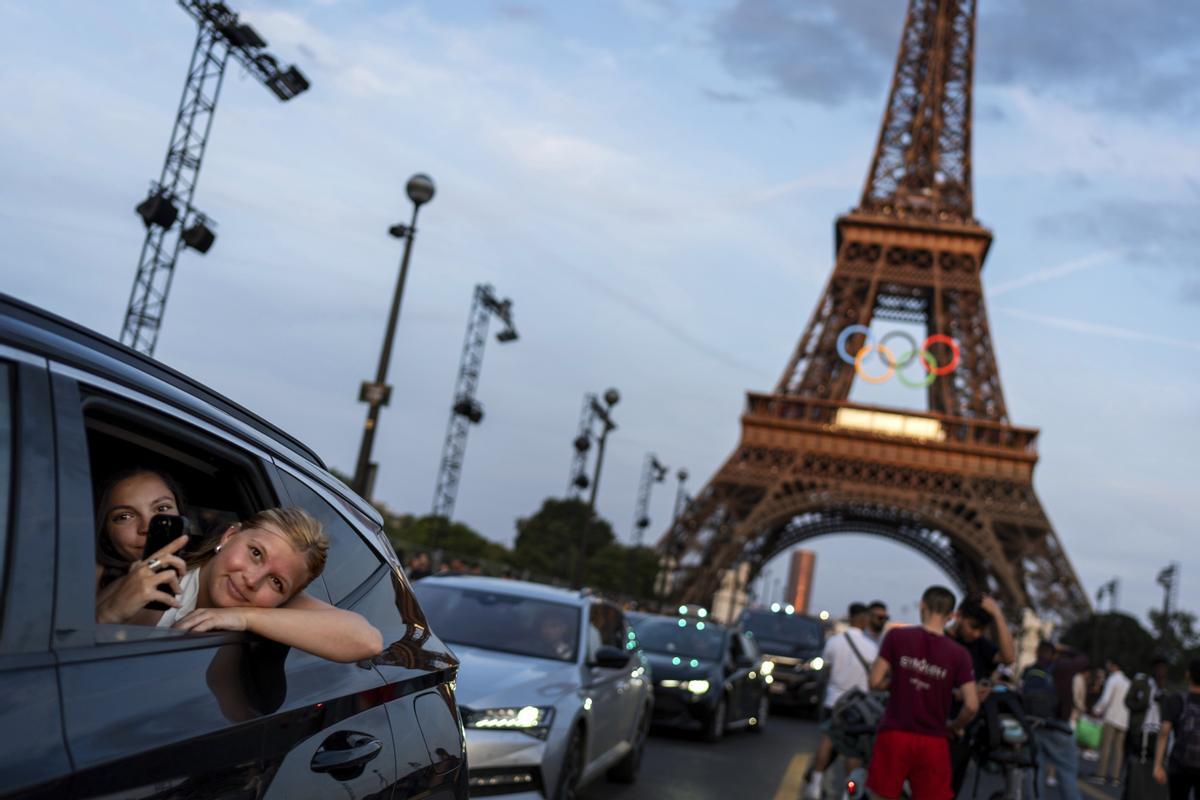 Passengers in the back of a taxi film themselves as they leave the Eiffel Tower decorated with the Olympic rings ahead of the 2024 Summer Olympics, Wednesday, July 17, 2024, in Paris. (AP Photo/David Goldman)