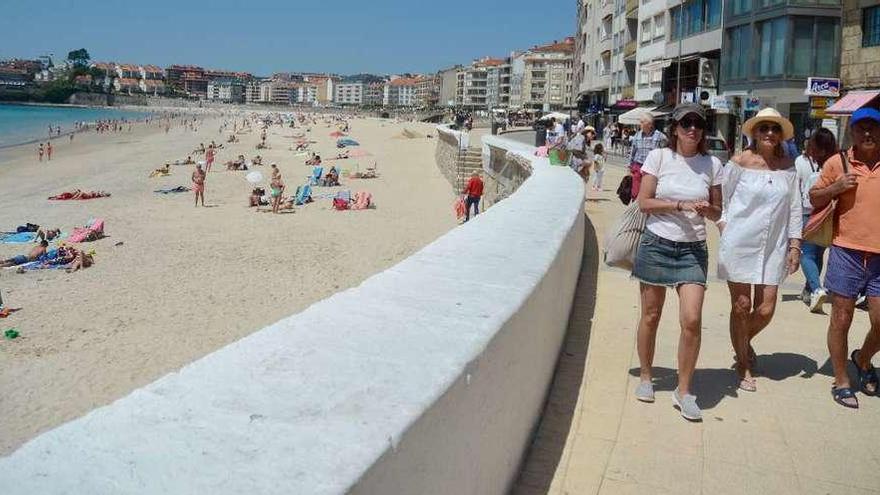 La playa de Silgar, con numerosos bañistas, y el paseo de Sanxenxo, también muy concurrido en la jornada de ayer. // Rafa Vázquez