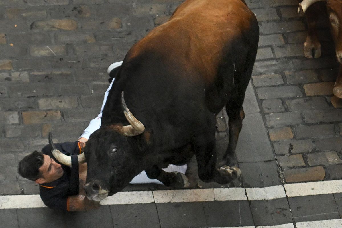 El almassorí Pablo Gil, enganchado a uno de los toros en el tercer encierro de San Fermín.