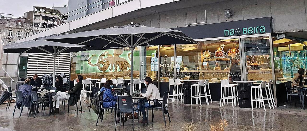 Clientes de un local hostelero del entorno del Náutico se protegen de la lluvia con sombrillas