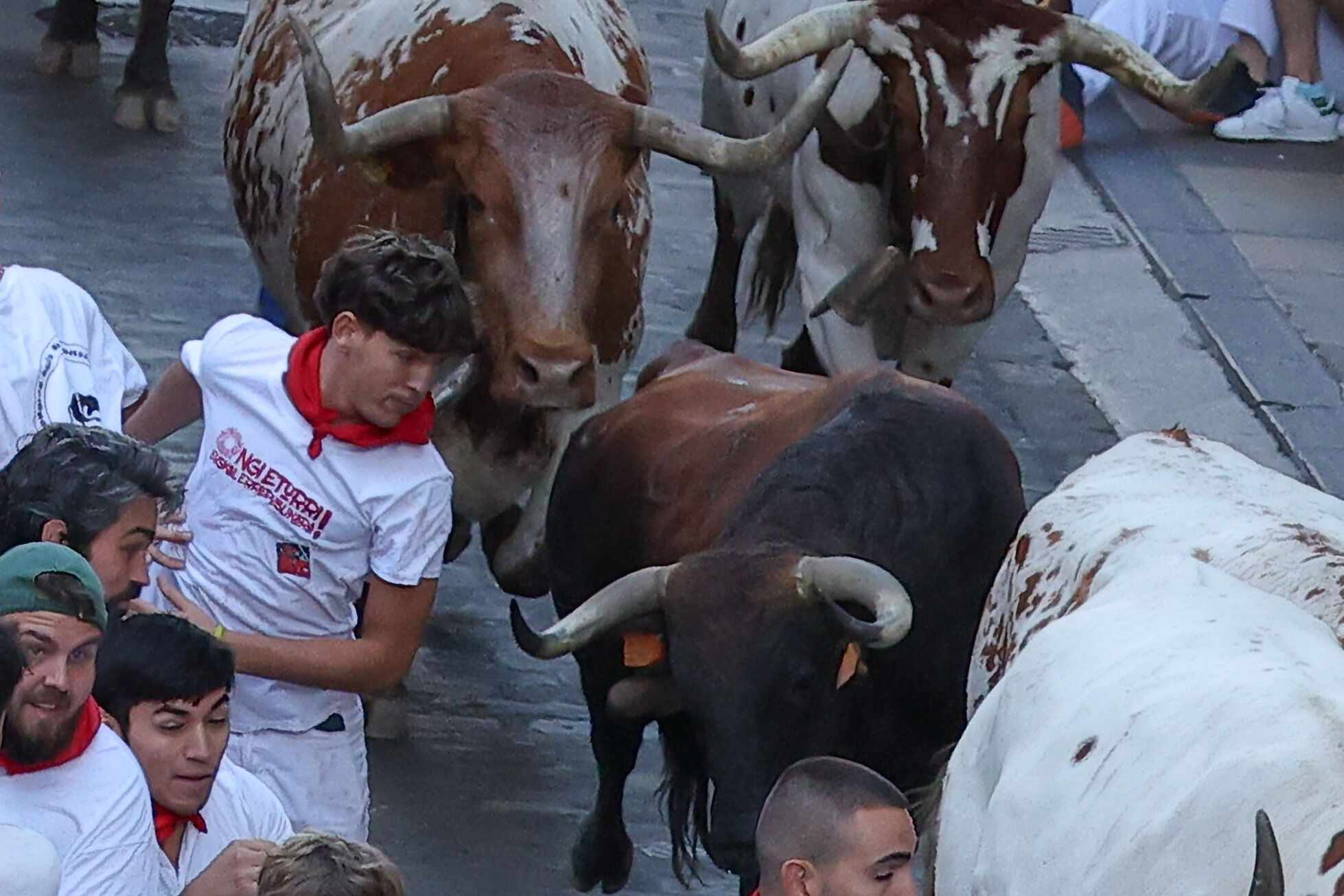 PAMPLONA, 08/07/2025.- Varios corredores son perseguidos por toros de la ganadería Cebada Gago en el tramo que va desde el final de la cuesta de Santo Domingo a la curva de Mercaderes, durante el segundo encierro de los Sanfermines este martes, en Pamplona. EFE/ J.P. Urdiroz