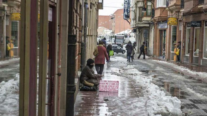 Una mujer pide en la calle Herreros tras una nevada hace tres inviernos.