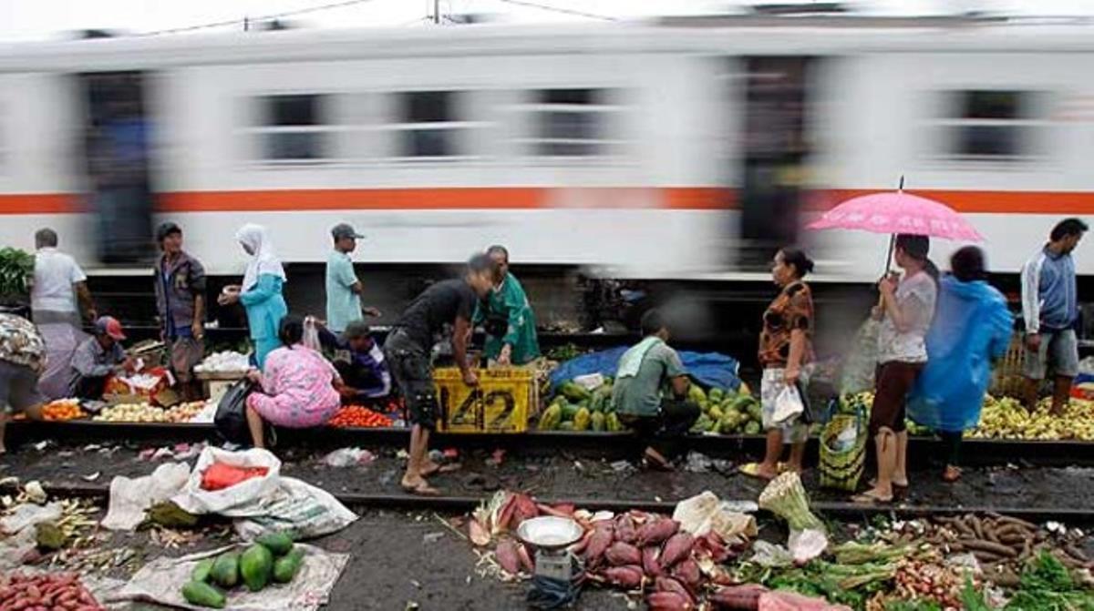 Un grup de persones compren fruita i verdures en un mercat situat al costat de les vies de tren, a Djakarta.