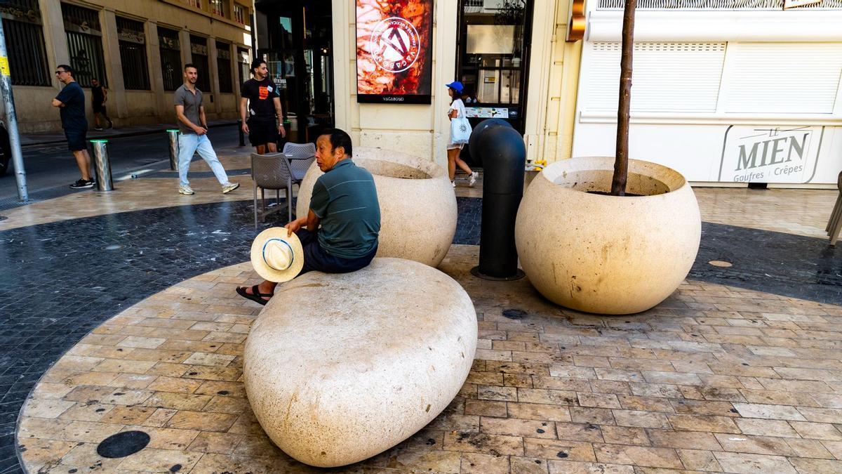 Un hombre descansa en la nueva zona peatonal de la Explanada, con el pavimento ennegrecido por la suciedad