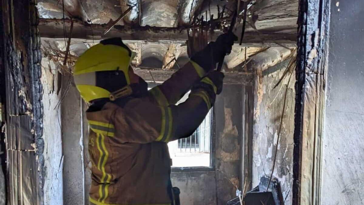 Un bombero interviene en la vivienda incendiada en Monzón