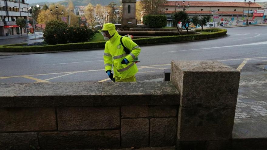 Un operario de limpieza, protegido, desinfectando la calle con la ciudad vacía detrás