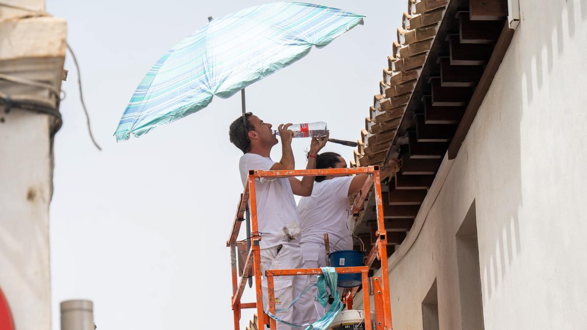 Unos trabajadores se cubren del sol con una sombrilla y beben agua en Granada, el martes pasado.
