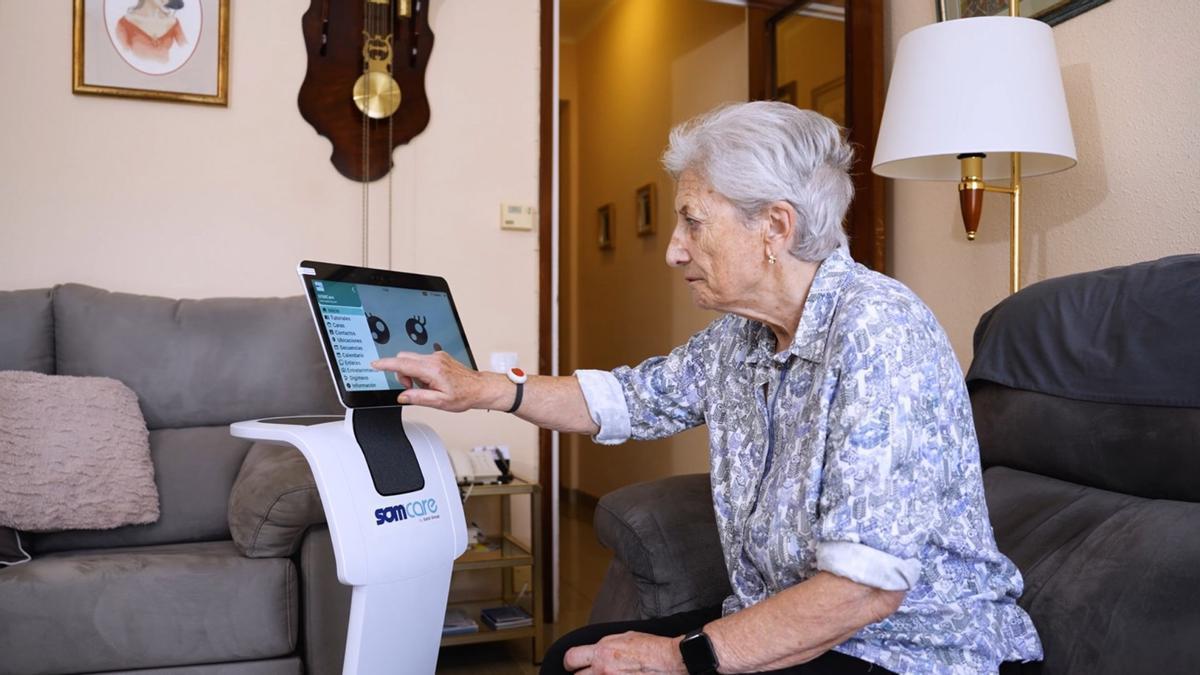 Una mujer de 91 años con un robot diseñado para ayudar a las personas mayores en su día a día.