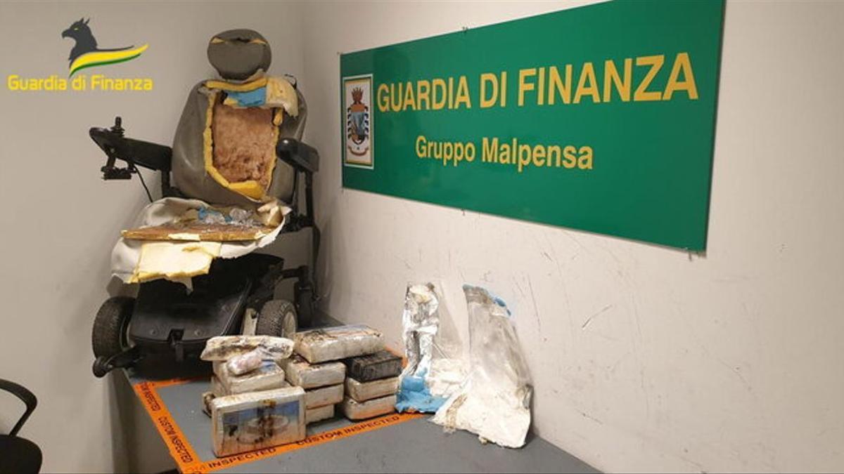 La droga incautada al traficante español en el aeropuerto de Malpensa (Italia) y la silla de ruedas que utilizó para ocultarla.