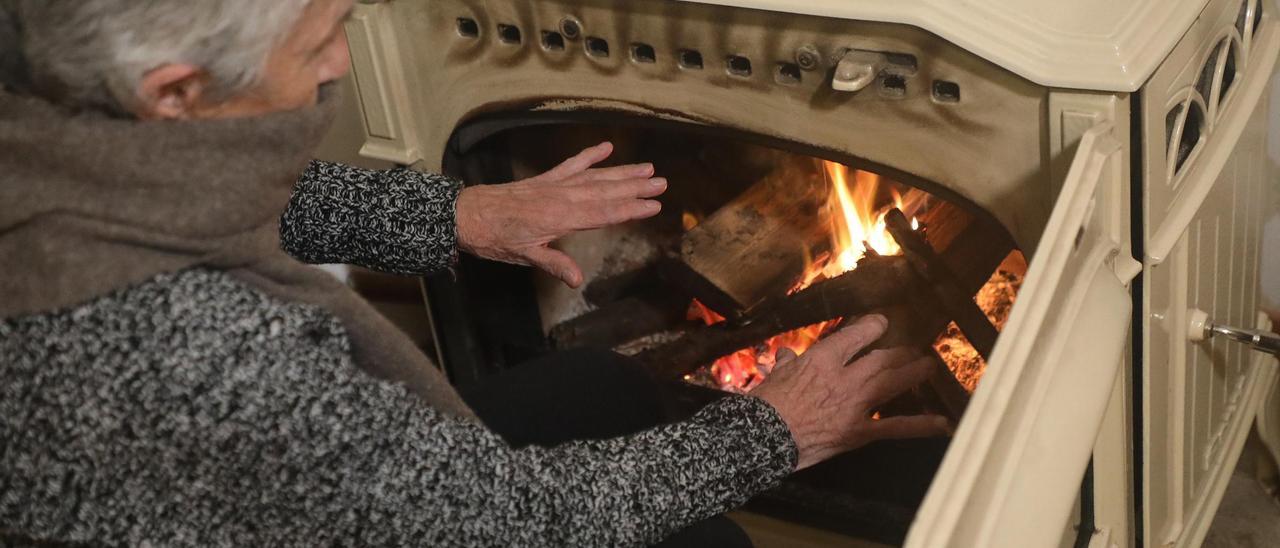 Una mujer se calienta las manos con una estufa de leña en un domicilio en Santiago.