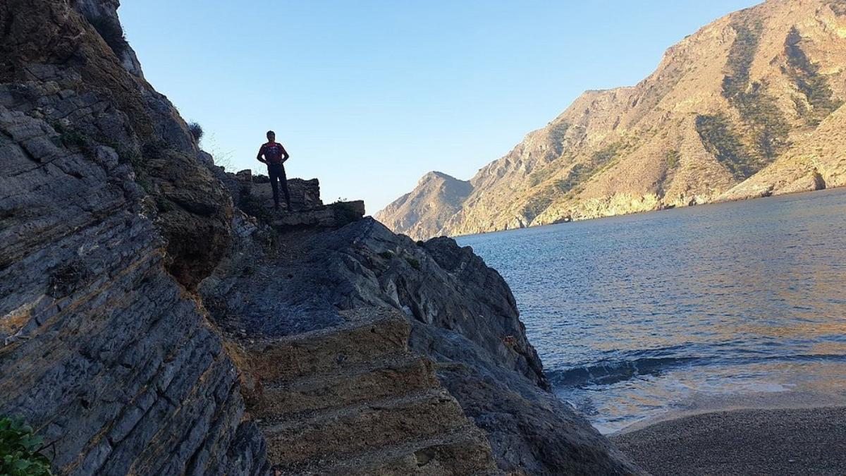 Una persona comienza una sesión de escalada junto a la cala.