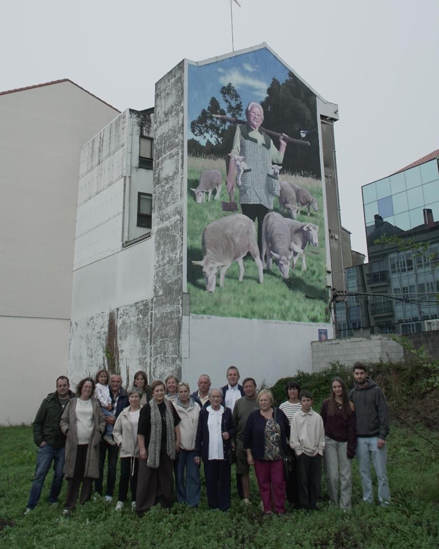 María da Orraca, arropada por sus ocho hijo y otros miembros de su familia, con el mural de fondo.
