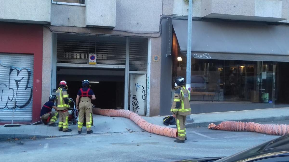 Los bomberos realizando la limpieza de aire del garaje afectado. // Alba Villar