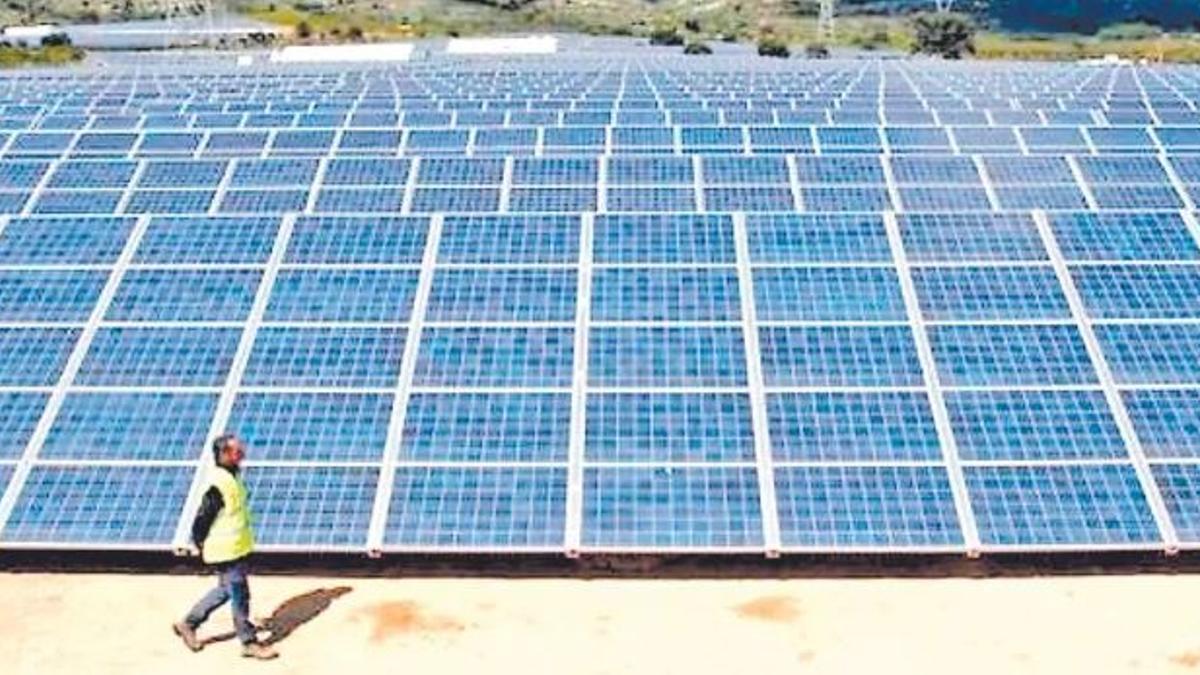 Un operario pasa ante una instalación fotovoltaica ubicada en la Comunitat Valenciana.