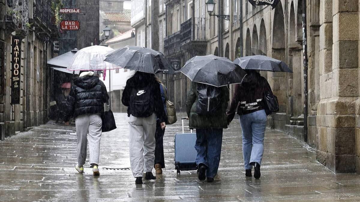 Un grupo de jóvenes camina por Santiago bajo un fuerte aguacero
