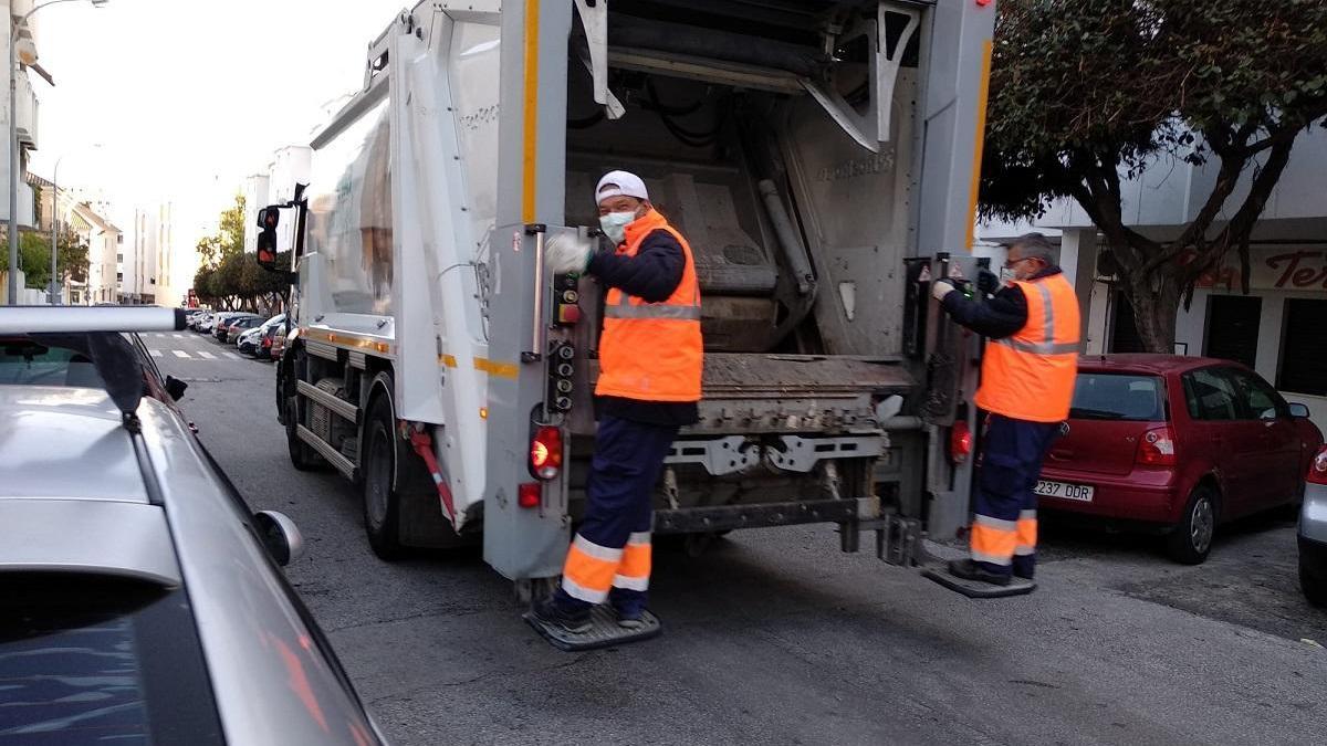 Dos operarios en un camión de limpieza por una de las calles del municipio.