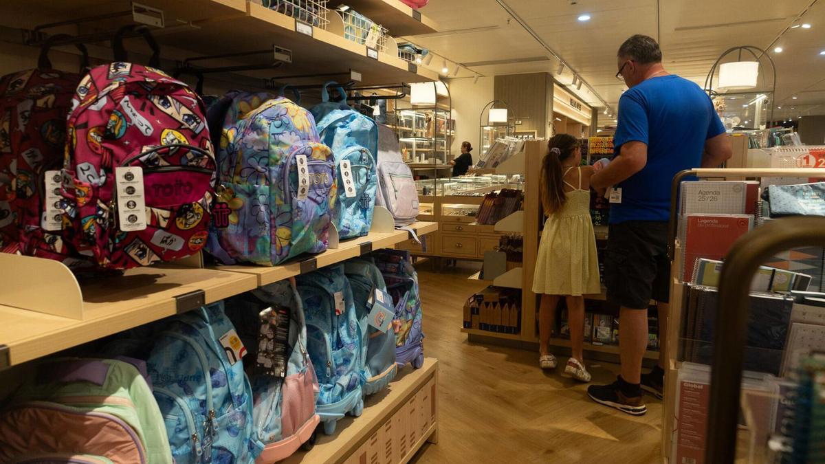 Un pare i una filla preparen la tornada a les aules comprant material escolar en un comerç