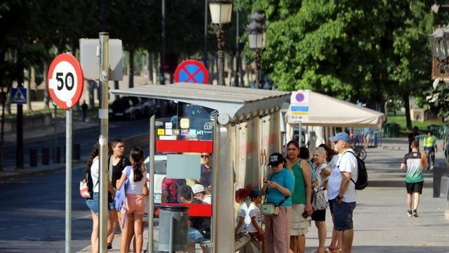 Diverses persones es refugien a l’ombra d’una parada d’autobús a l’avinguda Blondel de Lleida durant l’onada de calor