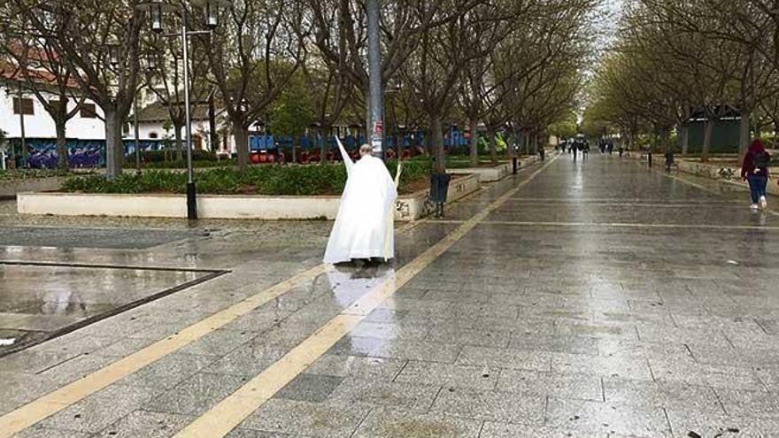 Un penitente con una  palma en la mano cruza el parque de ses Estacions tras la anulación de la procesión.