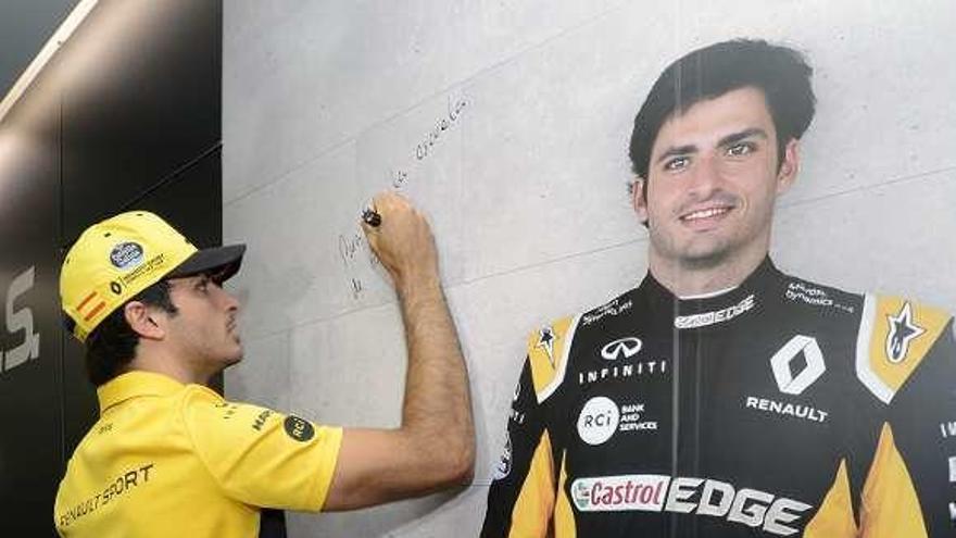 Carlos Sainz firma una pared con su imagen. // Efe