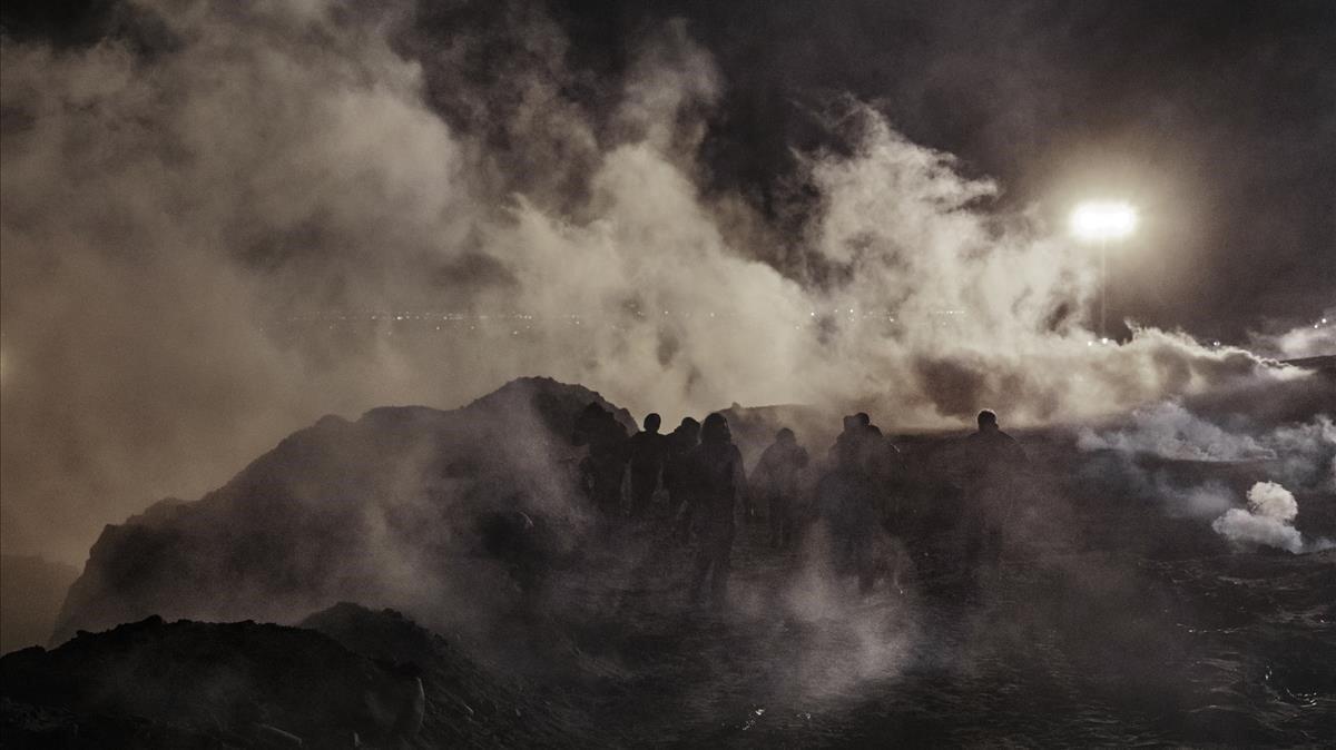 Emigrantes corren tras el lanzamiento de gases lacrimógenos, por parte de la US Border Patrol, al lado Mejicano de la verja.