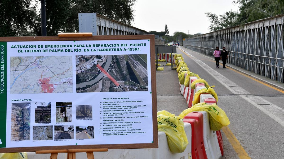 El Puente de Hierro de Palma del Río, cerrado parrcialmente al tráfico, es objeto de obras de reparación que se detallan en un panel explicativo.