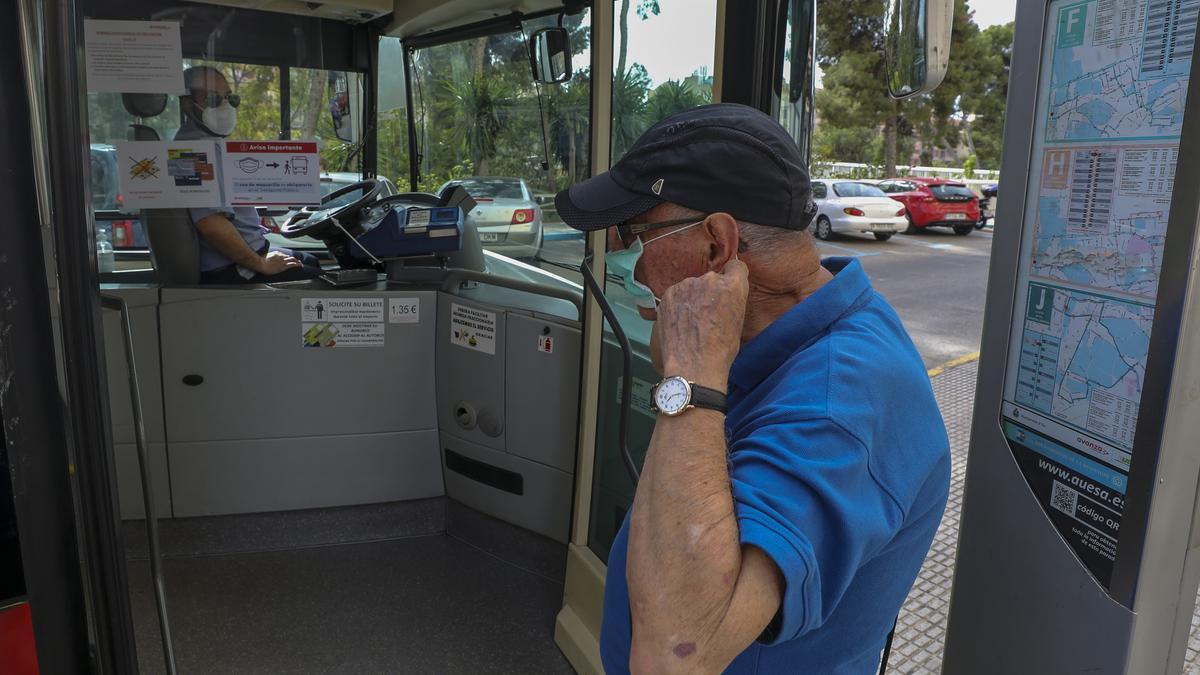 Un señor se pone la mascarilla antes de subir al autobús en Elche.