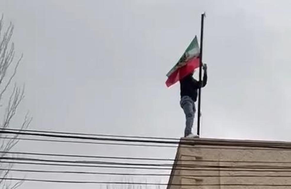 Un activista cambia la bandera de la Embajada de Irán en Madrid por la anterior a la revolución de 1979.