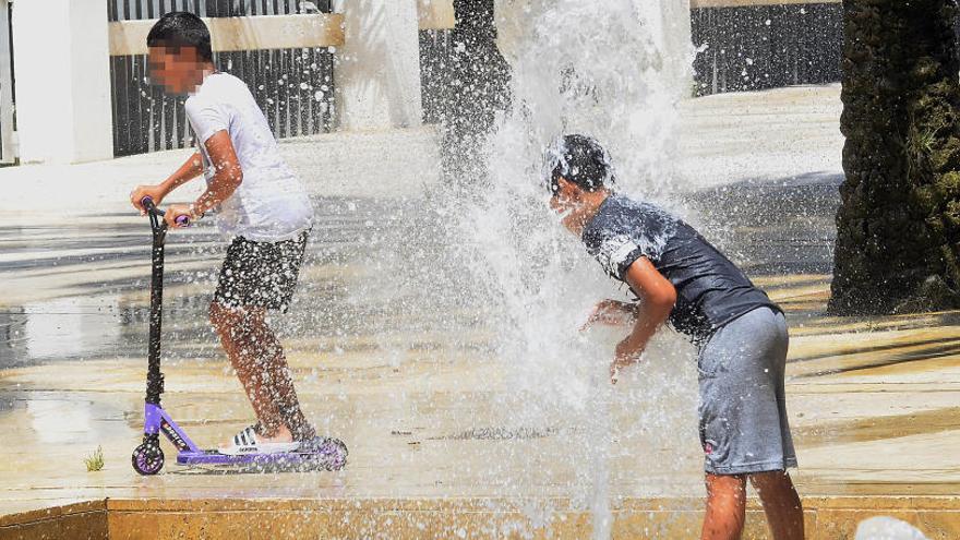 Unos niños se refrescan en una fuente de Elche