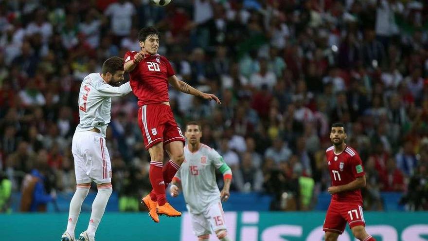 El iraní Azmoun se anticipa a Piqué, con Sergio Ramos al fondo.