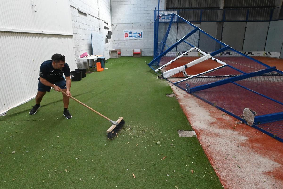 Un trabajador de SportPadel Burriana limpia los destrozos en la instalación.