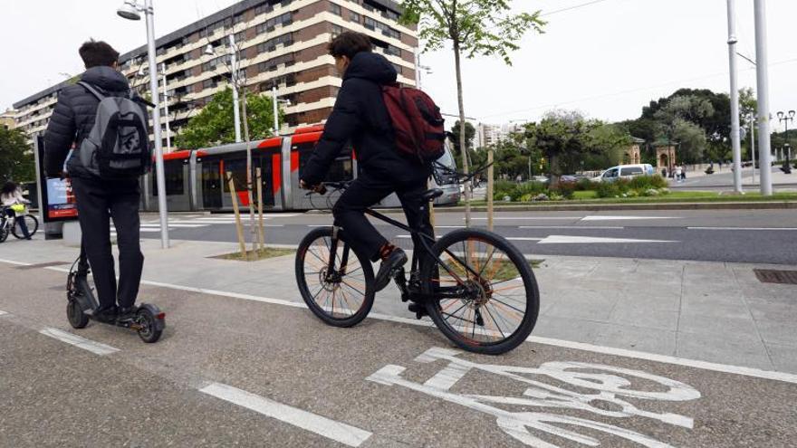 Dos jóvenes, uno en bici y otro en patinete, circulan por el carril bici del paseo Fernando el Católico.  | JAIME GALINDO