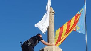 Un agente de la policía retira la bandera con versículos del Corán colgada en las Torres de Serranos (Valencia)