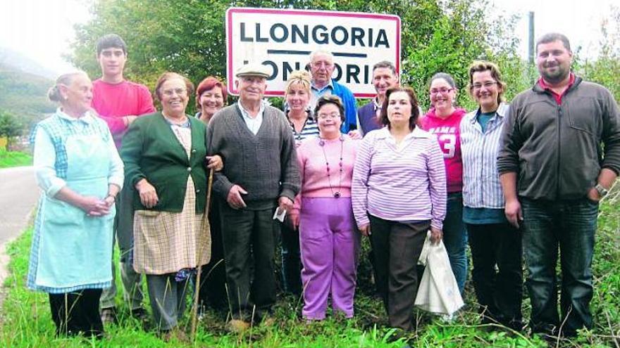 Los vecinos de Longoria, ayer, reunidos a la entrada del pueblo, junto al cartel. / lorena valdés