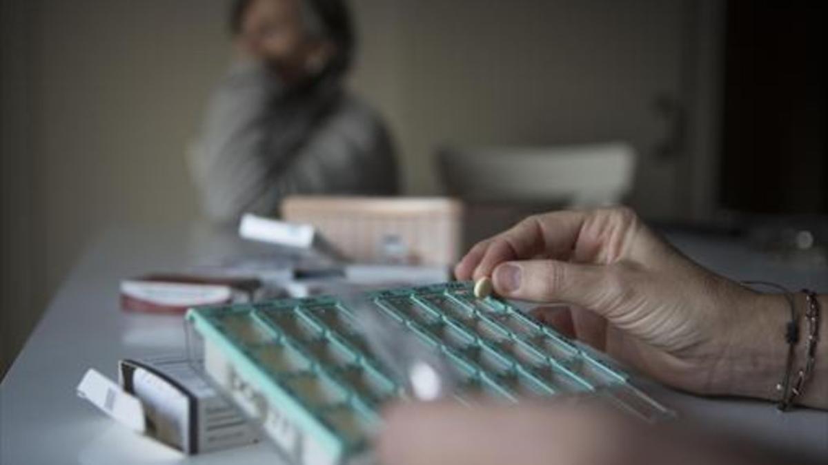 Un paciente coge una píldora de una caja de fármacos.