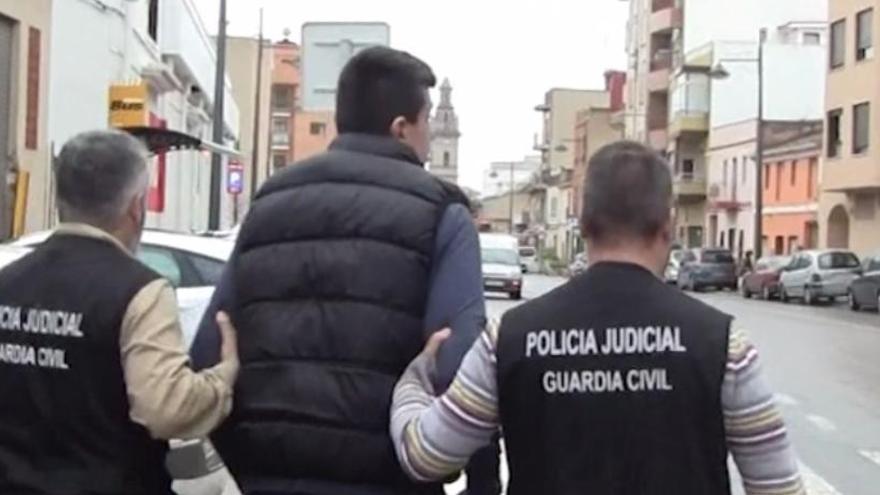 Dos de los investigadores escoltan al primer detenido en 2015.