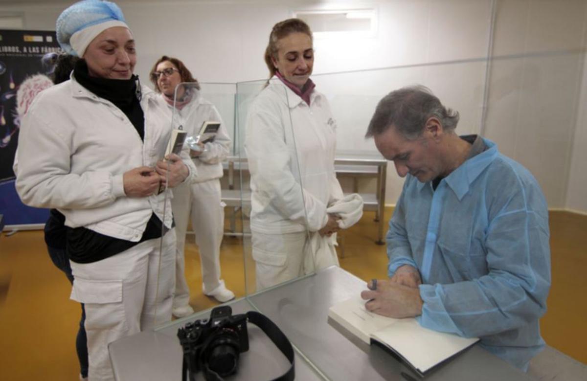 El escritor firmando los ejemplares a los trabajadores de la quesería que han participado en el programa. | Cedida