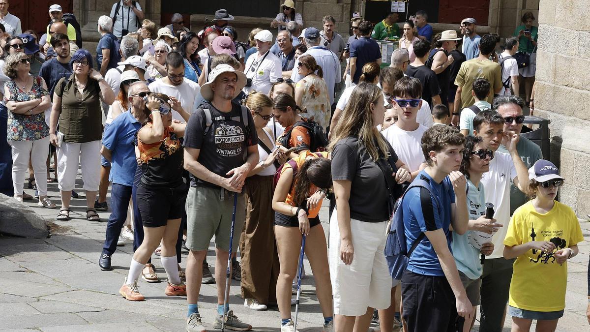 Un grupo de turistas y peregrinos aguardan para entrar en la Catedral de Santiago.