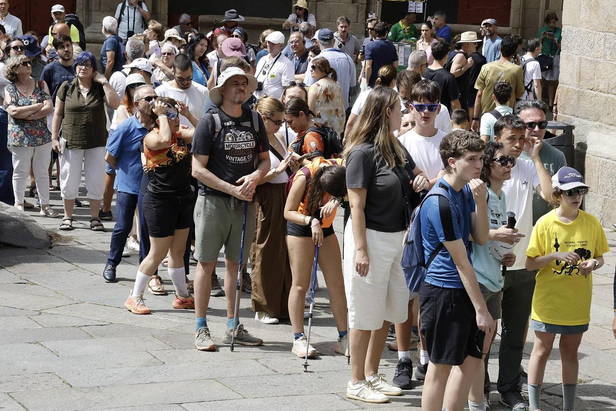 Un grupo de turistas y peregrinos aguardan para entrar en la Catedral de Santiago.