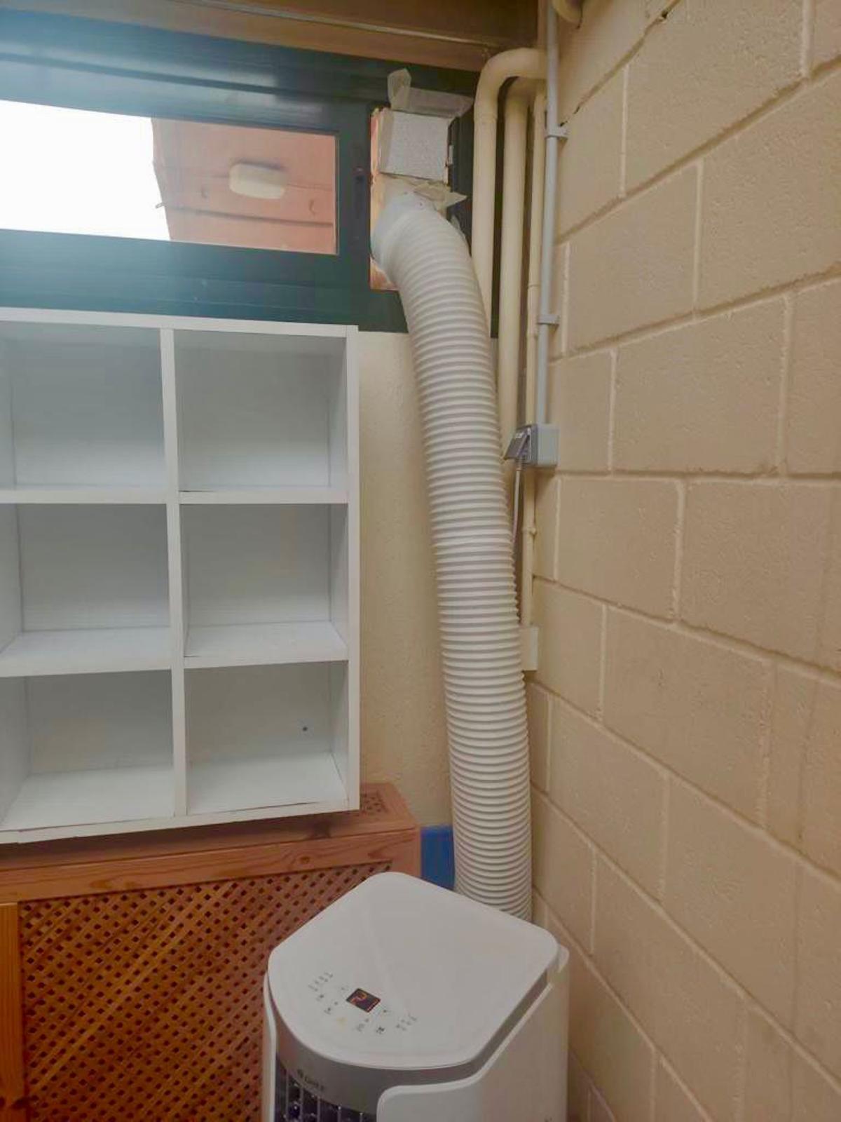 Un aparato de aire de una escuela municipal con el tubo saliendo por la ventana