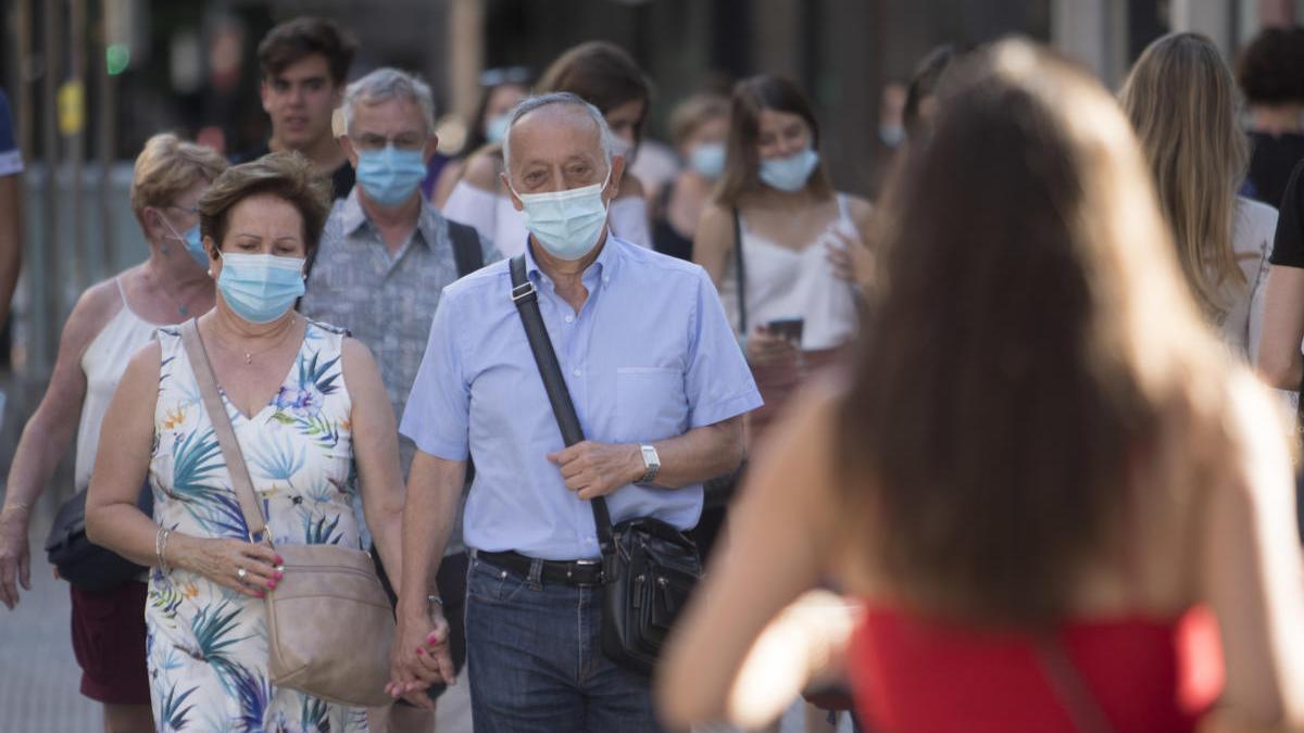 Una pareja camina con mascarilla.