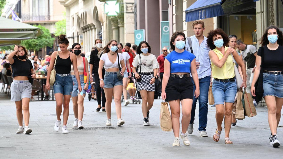 .Barcelona. 29.06.2021. Barcelona. Paseantes descendiendo por el paseo de Gracia, para todos los gustos en cuestión de llevar o no la mascarilla por la calle, cuando la normativa ya permite no llevarla obligatoriamente en espacios abiertos. Fotografía de Jordi Cotrina