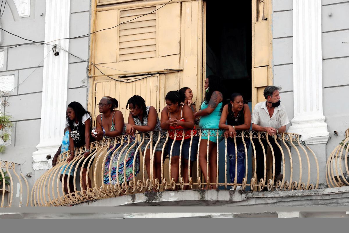 Varias personas observan desde su azotea las manifestaciones en La Habana.