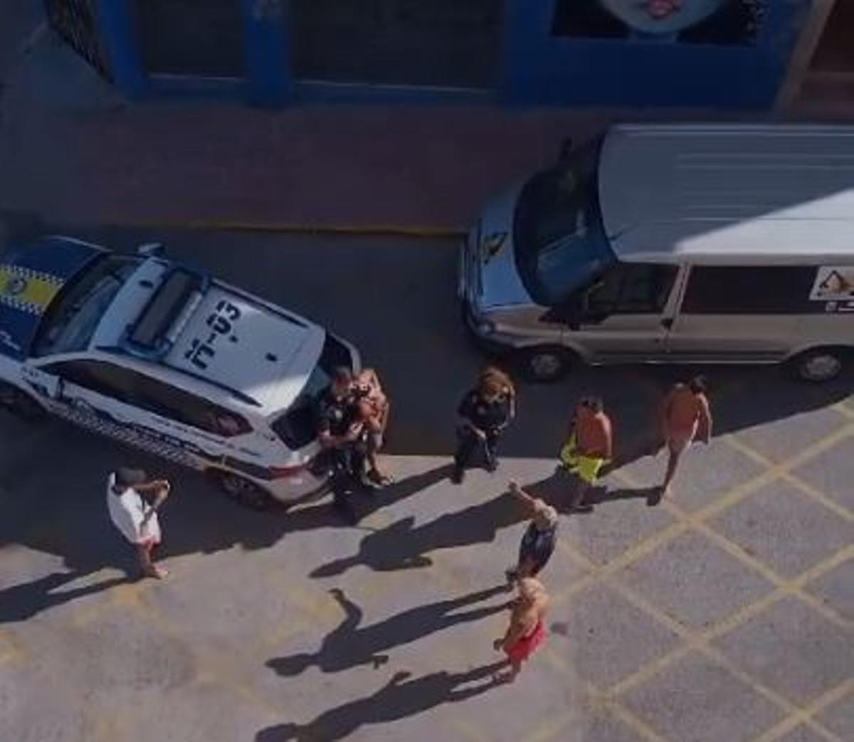 Imagen en la que se observa como el agente agredido después retiene el conductor rodeado de otras personas. También el vehículo mal estacionado