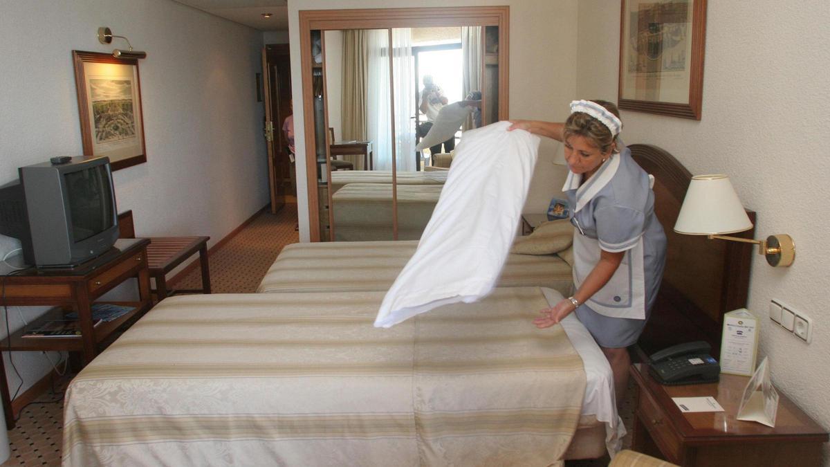 Una camarera de piso hace la cama en un hotel.