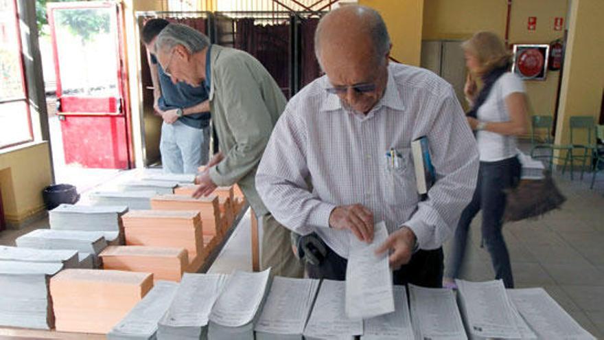 Varios madrugadores escogen sus papeletas para emitir su voto en un colegio de Aravaca, nada más abrirse las mesas electorales para los comicios autonómicos y municipales que se celebran hoy.