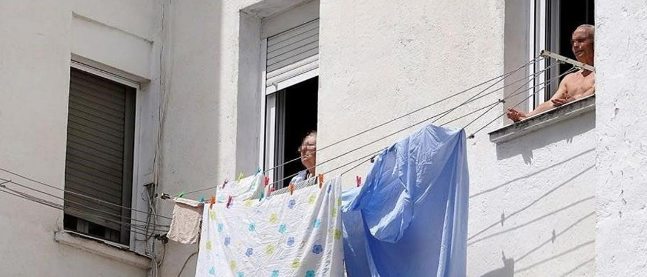 Dos personas mayores toman el sol en la ventana vivienda en Madrid. José Luis Roca