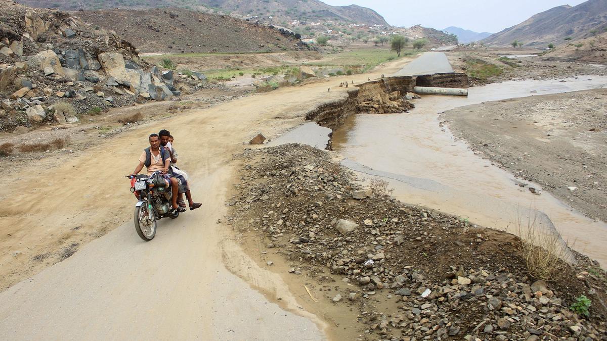 Unos hombres pasan por una zona inundada en Yemen.