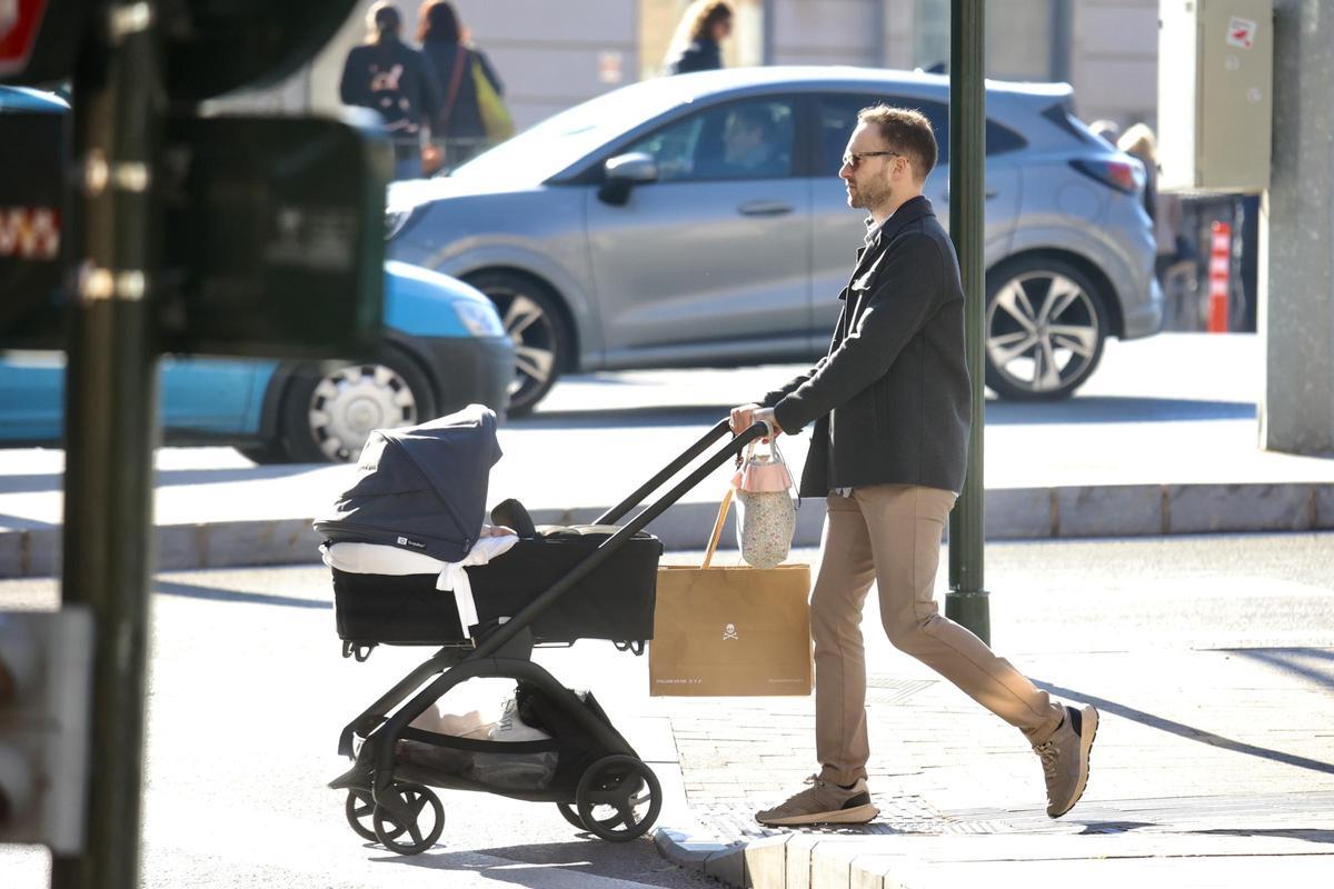 Un hombre pasea con su bebé en un carrito por las calles del centro de Murcia.